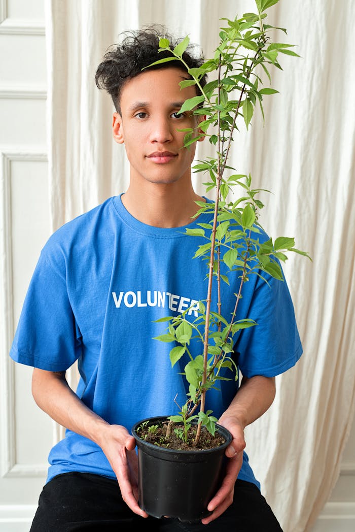 Young adult holding a potted plant, symbolizing volunteerism and environmental care.